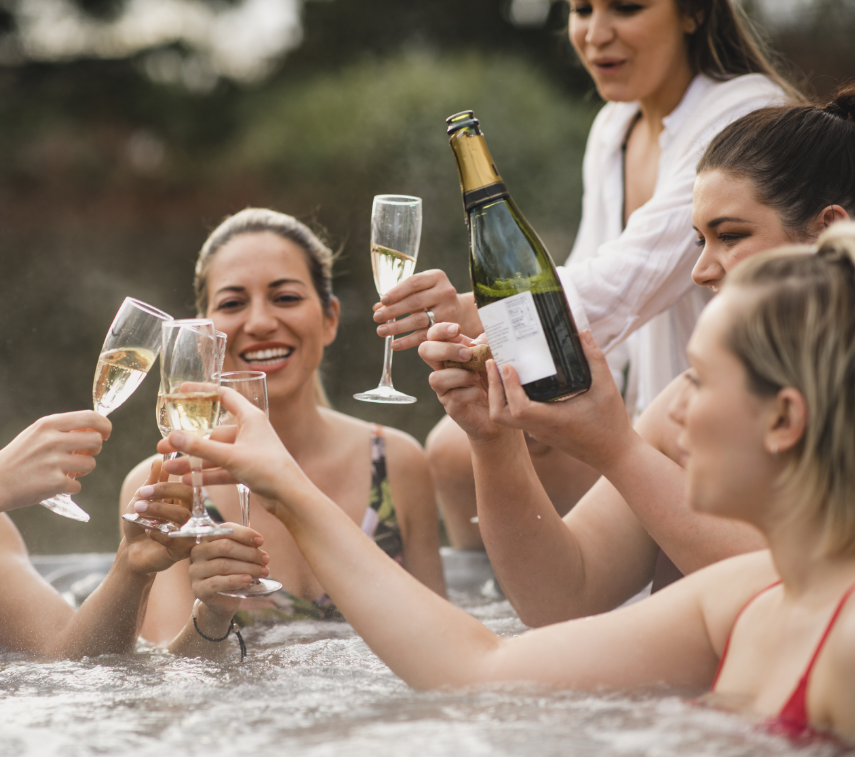Freundinnen trinken Champagner und haben Spaß in einem Badefass.