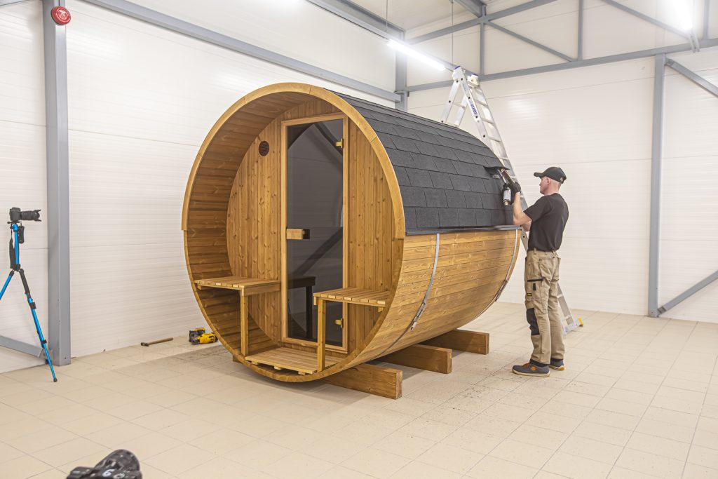 Ein Mann baut eigene Sauna in einem Werkstatt auf.